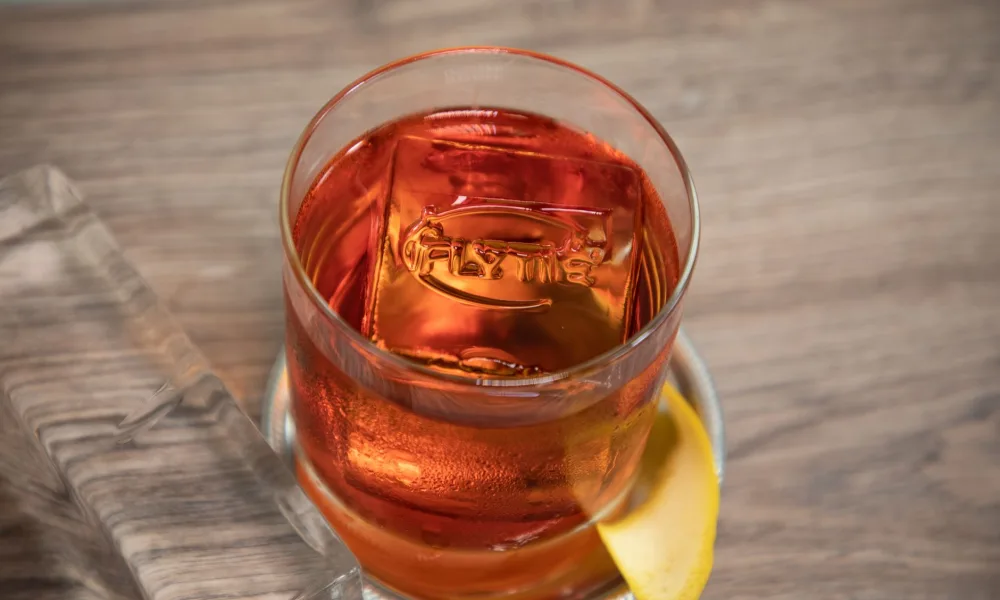 clear ice cube next to cloudy ice cube in glass