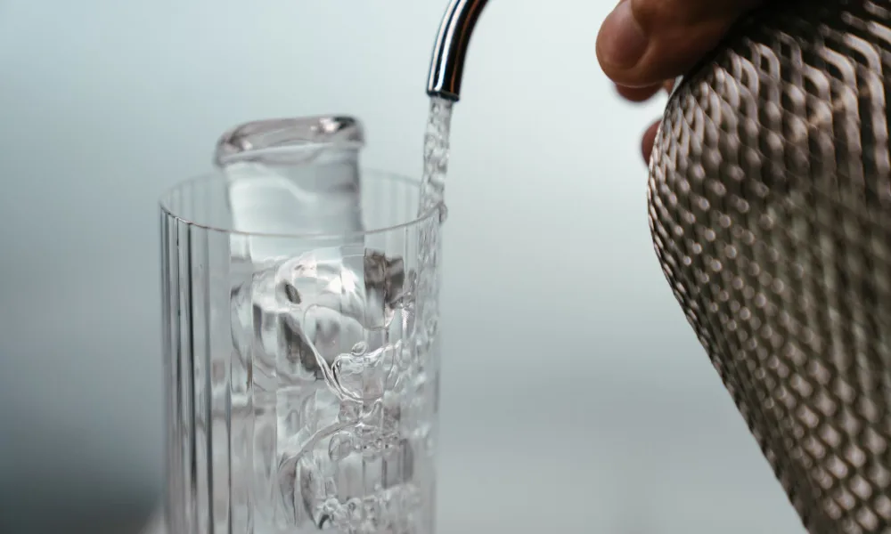 glass of water with bullet ice cubes next to portable ice maker