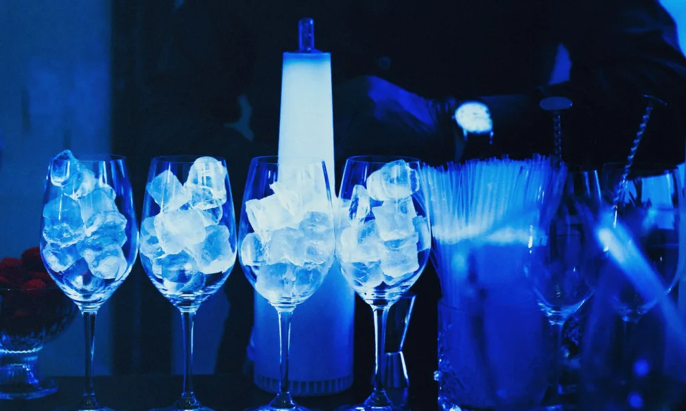 person filling multiple glasses with ice from countertop ice maker