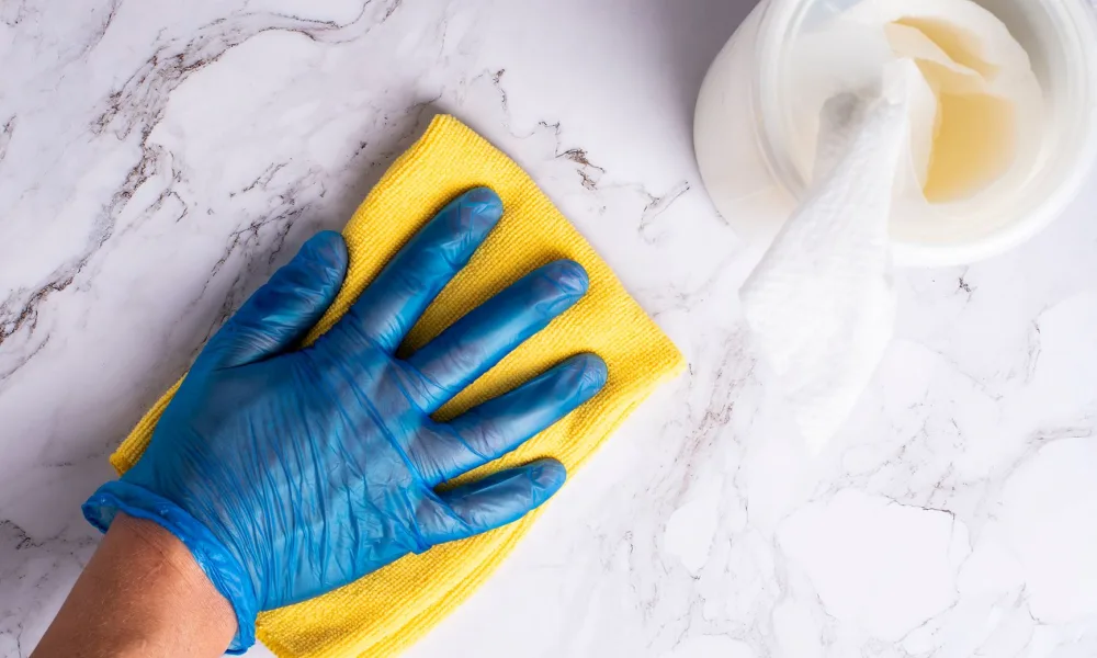 person wiping down countertop ice maker reservoir with cloth