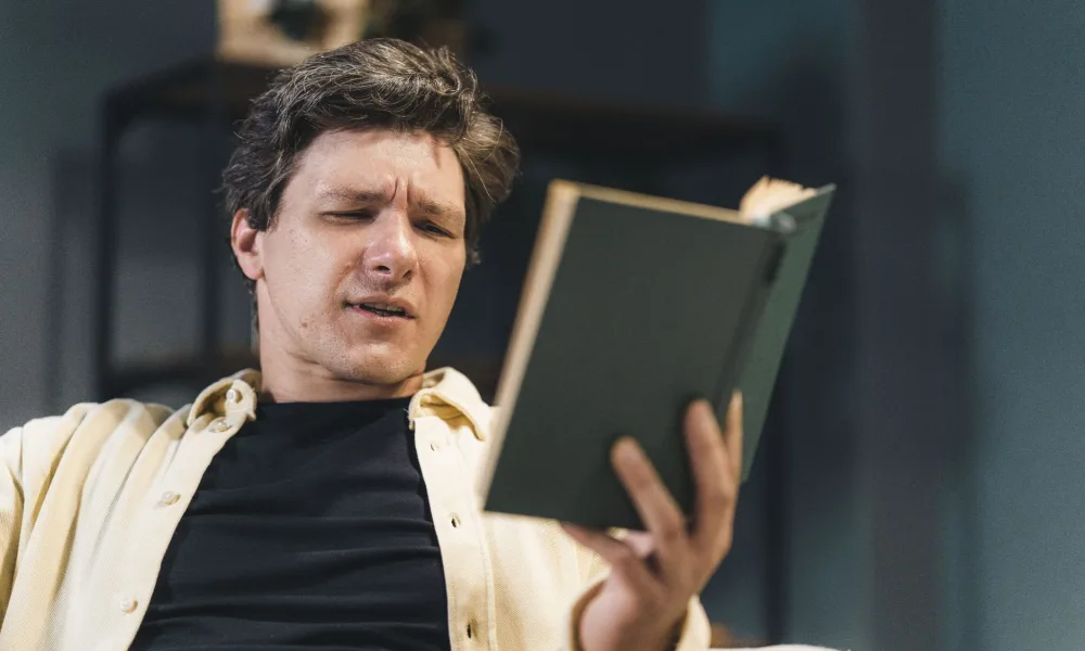 confused person reading ice maker manual next to machine