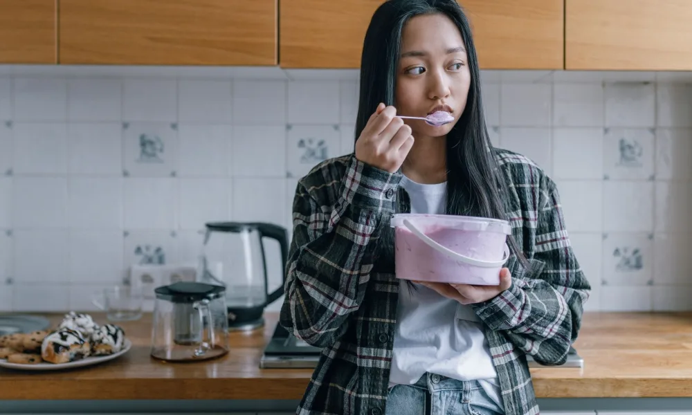person tasting ice cube with concerned expression in kitchen